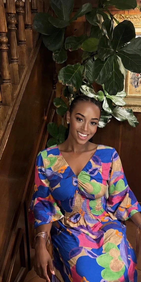 Faith Adjarhore, founder of DDI, smiling on a wooden staircase